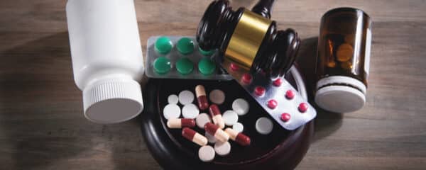Several prescription drugs in pill form on a table with a judge's gavel
